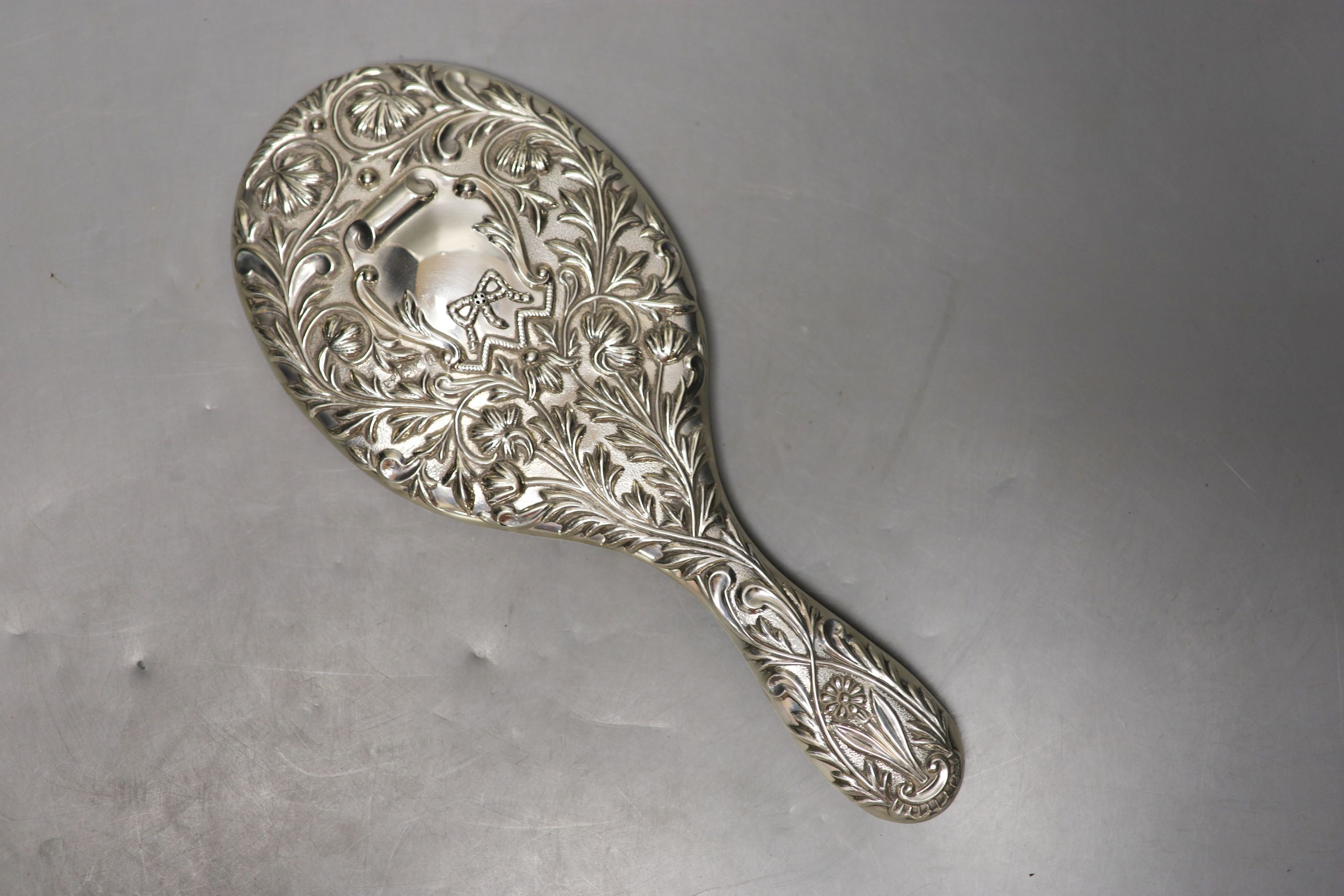 A late Victorian repousse silver mounted hand mirror, London, 1899, two silver mounted glass toilet jars, a silver handled button hook, silver handled shoe horn and a clothes brush.